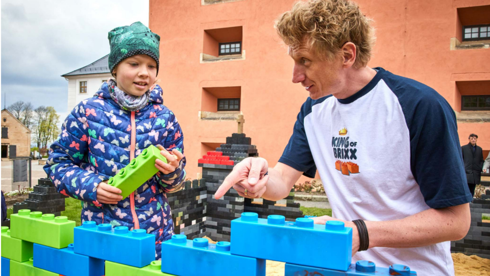 Abby (l.) und Björn Freitag, Gewinner der TV-Sendung „Lego Masters“ und Moderator der Online-Sendung „King of Brixx“, bauen zusammen einen Teil der Maxoli-Bricks-Burg auf. ©Marko Förster/Festung Königstein gGmbH