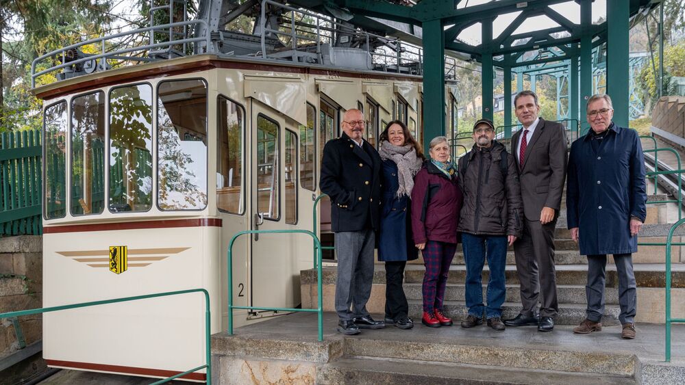 Bei einem Vororttermin an der Dresdner Schwebebahn wurde auf den Weltpankreaskrebstag am 21. November 2024 und die damit verbundene Lichtaktion aufmerksam gemacht (v.l.): Prof. Michael Albrecht, Medizinischer Vorstand UKD, Anja Polenz, Leiterin Kommunikation DVB, Wolfgang Korneli (mit Ehefrau), Pankreaskrebspatient, Prof. Jürgen Weitz, Direktor Klinik für Viszeral-, Thorax- und Gefäßchirurgie, Dr. Andreas Sperl, Vorsitzender des Stiftungsvorstandes der Stiftung zur Förderung der Hochschulmedizin Dresden; Foto: UKD/Kirsten Lassig