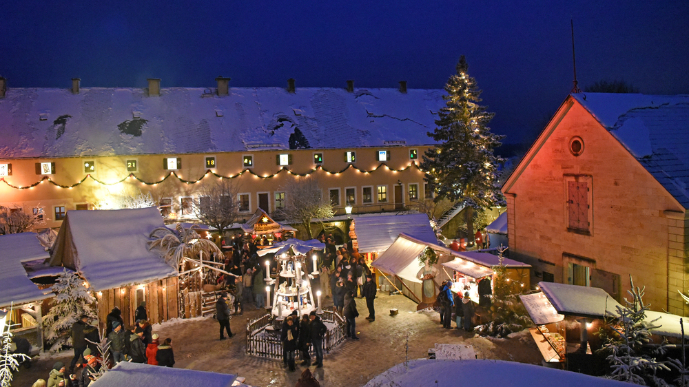 Blick auf die Marktbuden auf dem Paradeplatz; vorn die drei Meter hohe Erzgebirgische Weihnachtspyramide, hinten die Alte Kaserne mit dem längsten Adventskalender Deutschlands.  Copyright:Festung Königstein gGmbH