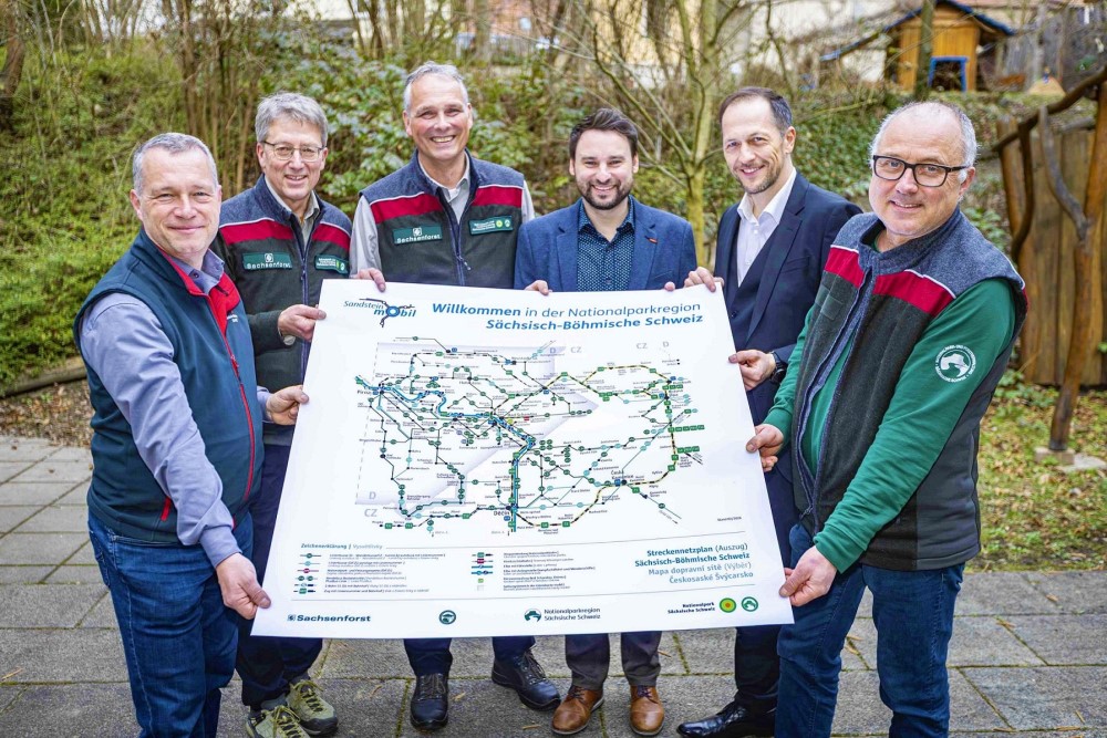 Foto: Marko Förster Das jüngste Ergebnis der Fahrtziel Natur-Trägergruppe Sächsische Schweiz ist der aktualisierte und wesentlich erweiterte grenzüberschreitende Liniennetzplan der Nationalparkregionen. V. l. n. r.: Tino Richter (Vorsitzender Tourismusverband Sächsische Schweiz), Hanspeter Mayr (Sprecher Nationalpark-und Forstverwaltung Sächsische Schweiz), Uwe Borrmeister (Leiter der Nationalpark- und Forstverwaltung Sächsische Schweiz), Rico Manns (Projektkoordinator für Verkehrs- und Parkleitsystem beim Verein Landschaf(f)t Zukunft e. V.), Thomas Kunack (Bürgermeister von Bad Schandau) und Jörg Weber (Stabsstelle NLPFV und Redaktion)